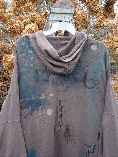 Barclay Hemp Cotton Open Front Hooded Cloak Twig Stone OSFA displayed on a hanger, showcasing its cozy hood, kangaroo pockets, dolman sleeves, and twig-themed painting on the back.