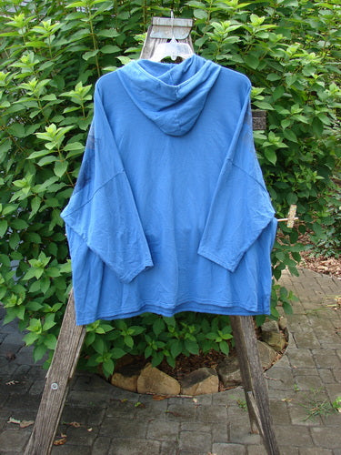 Barclay Dolman Roo Pocket Hoodie Mixed Theme Skylark OSFA displayed on a wooden rack, showcasing its cordless hood, long sleeves, and unique painted pockets, embodying Bluefishfinder.com's vintage, expressive fashion ethos.