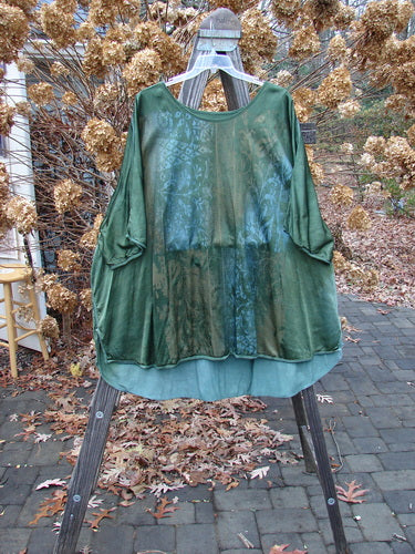 Barclay Viscose Hi Low Tunic Wildflower Forest Sun Size 2 displayed on an outdoor swing with a rounded neckline, varying hem, vented sides, and three-quarter dolman sleeves, featuring a wildflower theme pattern.