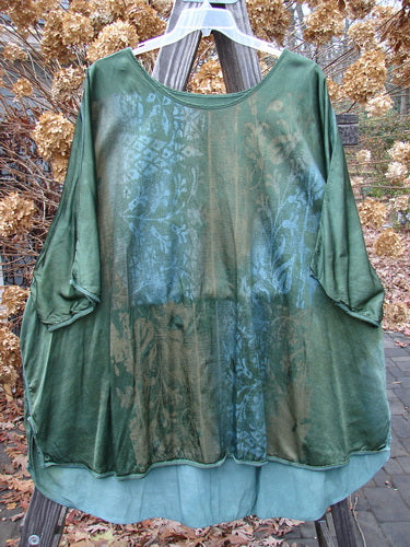 Barclay Viscose Hi Low Tunic Wildflower Forest Sun Size 2 displayed on a pole, showcasing a rounded wider neckline, three-quarter-length dolman sleeves, vented sides, and a beautifully blended wildflower pattern.