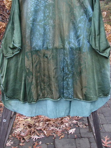 Barclay Viscose Hi Low Tunic Wildflower Forest Sun Size 2 hanging on a rack, showcasing a rounded wider neckline, varying hem, and three-quarter length dolman sleeves with exterior stitching.