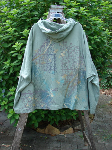 Barclay Hooded Postcard Zipper Jacket Vest Rear Garden Trellis Sage OSFA displayed on a hanger, highlighting its generous hood, dolman shoulders, and unique rear garden trellis design, capturing its cozy, artistic essence.