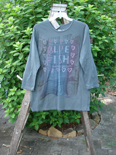 Barclay NWT Long Sleeved Studio Tee Blue Fish Love Thoreau Size 0 on a swinger, showcasing its rounded neckline and long sleeves, complemented by the classic Blue Fish Love theme print.