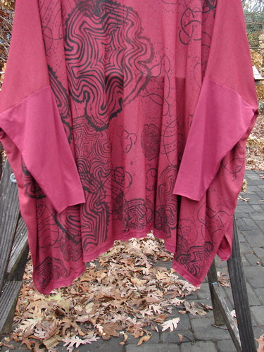 Barclay NWT Rayon Lycra Celebration Cardigan Spirograph Rouge OSFA displayed on a wooden rack, showcasing its open front, varying hemline, single front pocket, and flutter hem design.
