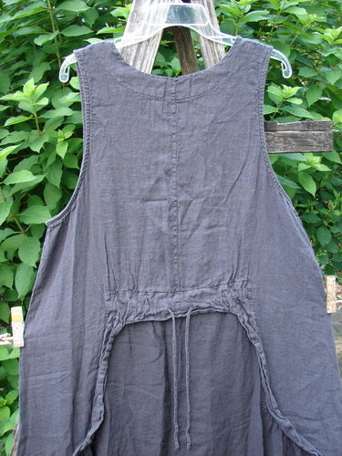 Barclay NWT Linen Explorer Jumper Contour Garden Black Sand Size 0 displayed outdoors, showcasing its unique full-bodied shape, scoop neckline, and distinctive exterior pockets against a natural setting.