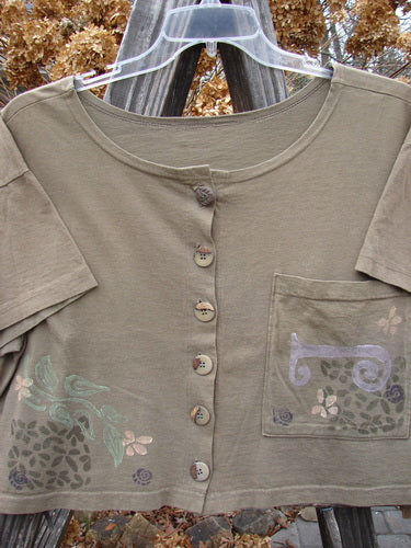 1994 Song Top Garden Bark Size 1: Close-up of the shirt showcasing its wide, boxy shape, slightly shallow neckline, vintage buttons, and an oversized front breast pocket with mixed theme paint.