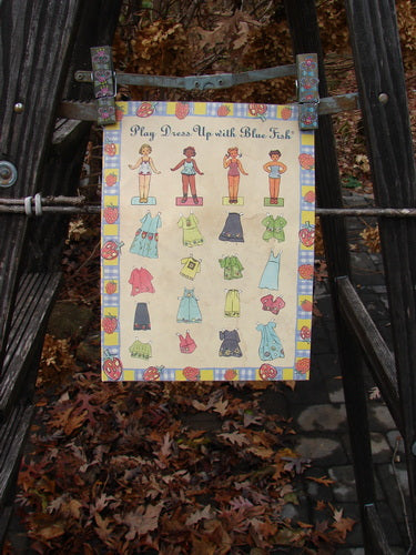 1999 Spring 2 Catalog Play Together One Size: A poster featuring a paper doll on a ladder, surrounded by autumn leaves, showcasing art and vintage imagery from the Blue Fish Spring 1999 collection.