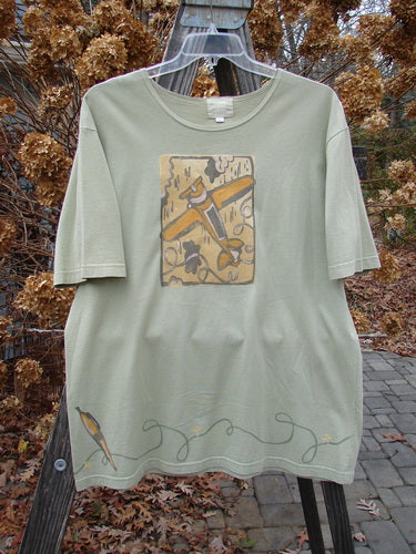 2001 Short Sleeved Tee Glider Plane Kelp Size 1 displayed on a swinger, featuring a glider plane graphic and Blue Fish logo on the back, with wide short sleeves and a slightly thinner neckline.