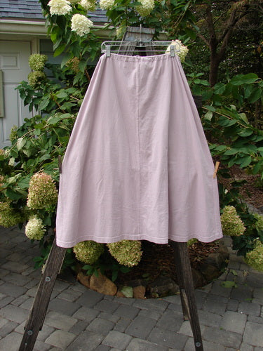 1994 PMU Patched Scoop Pocket Skirt with a drawstring waist and painted scooped pockets, hanging on a clothes rack; features a sweeping A-line shape and sectional panels.