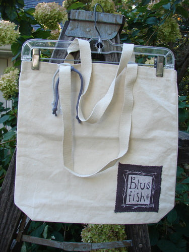 1998 PMU Patched Organic Cotton Canvas Tote Bag Oak Leaf Natural One Size displayed on a swinger, featuring blue logo patch and oak leaf patches, showcasing Bluefishfinder.com's commitment to sustainable upcycled vintage designs.