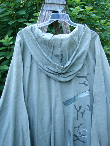 Close-up of the 1997 Linen Seaspray Jacket Bamboo Lagoon Size 3 showcasing its oversized floppy drawcord hood, dolman sleeves, and metal buttons, reflecting vintage Blue Fish Clothing's creative expression.