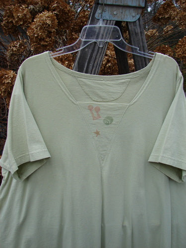 1994 Leaf Top Music Garden Aloe Size 2: Classic green shirt on a clothes hanger, featuring a unique 4 point hemline and a big tailored swing.