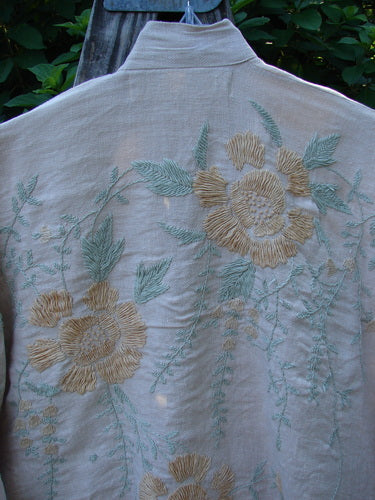 Magnolia Pearl Linen Embroidered Claudio Kimono Lilac Water OSFA features an open front, widening shape, three-quarter sleeves, and intricate pastel floral embroidery on medium-weight linen, embodying vintage-inspired elegance.