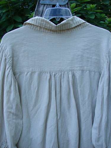 Magnolia Pearl Linen Crop Artist's Pocket Pullover features a unique Henley button front with a crinkled lace bib, three-button cuffs, and a yoke back, elegantly displayed against lush greenery.