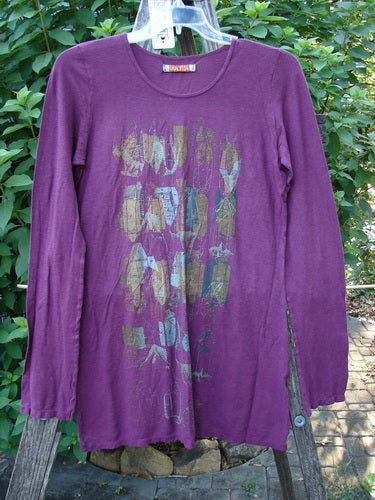 Barclay NWT Slub Cotton Hemp Long Sleeved Simple Tee Crystal Tyrian Berry Size 1 displayed on a swing, showcasing its rounded neckline, longer straight shape, and full-length sleeves with a crystal theme design.