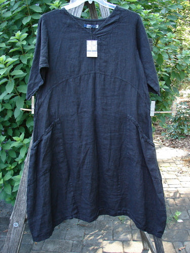 Barclay NWT Linen Cross Over Serenade Urchin Dress Unpainted Black Size 0, featuring a unique one-sided crossover neckline, empire waist, and varying hemline, displayed hanging on a clothesline.