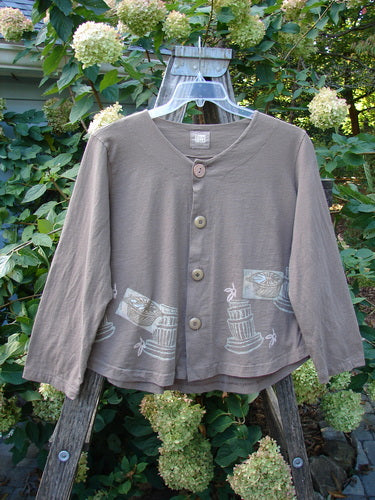 1999 Coffee Top Fancy Pot Riverbed Size 1, featuring a distinctive flowerpot theme and sweeping hemline, with big button closures and drawcord back. Made from organic cotton, showcased against a subtle plant backdrop.