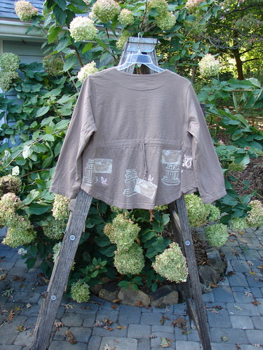 1999 Coffee Top Fancy Pot Riverbed Size 1 displayed on a wooden rack, showcasing its unique flowerpot theme paint, rounded hemline, and big button closures from Blue Fish’s 1999 Spring Collection.