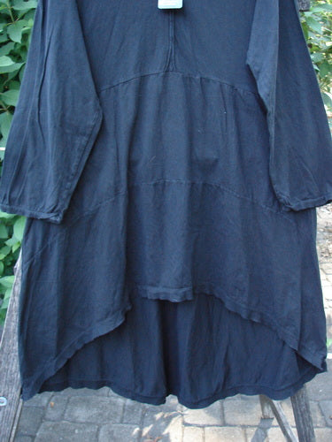 Barclay NWT Hi Low Hooded Pocket Tunic Unpainted Black Size 0 displayed on a swinging hanger, showcasing its cordless hood, raw-edged sleeves, empire waist, and dual front pockets.