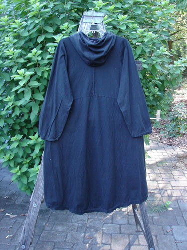 Barclay NWT Hi Low Hooded Pocket Tunic Unpainted Black Size 0 displayed on a wooden rack, showcasing its cordless hood, raw-edged sleeves, and flared swing design, embodying BlueFishFinder's unique vintage style.