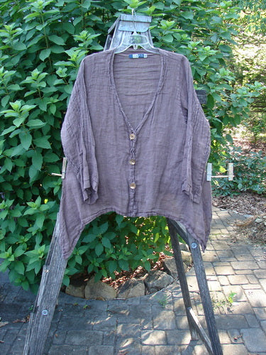 Barclay Linen Deep V Neck Three Button Top in Unpainted Peat, showcasing three-quarter pinched sleeves and a unique dippy hemline, displayed on a wooden stand, embodying BlueFishFinder's vintage style.