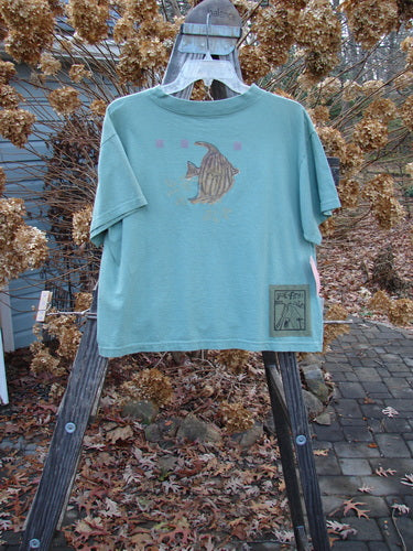 1994 NWT Short Sleeved Tee Fish Bowl Seagrass Size 3, displayed on a hanger, featuring a shallow ribbed neckline, slight bottom flair, and a painted fish bowl theme on blue cotton jersey.