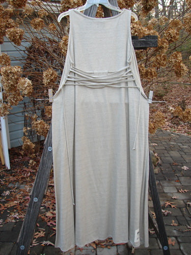 1998 Linen Knit Wrap Dress Unpainted Natural Size 2: A white dress on a wooden ladder, with a flowing linen knit. Features include a continuous bodice wrap, cord keepers, and a rounded rolled neckline. Bust 46, Waist 50, Hips 54, Sweep 80, Length 54 inches.