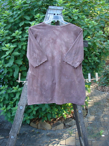 Barclay Cotton Lycra Three Quarter Sleeved A Line Tee Roots Mottled Clay Size 1 elegantly draped on a wooden ladder, showcasing its unique A-line shape and rolled neckline in an outdoor setting.