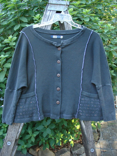 Barclay Thermal Exterior Stitch Two Pocket Jacket Geos Army Size 0 displayed outdoors, highlighting its rounded neckline, long narrowing sleeves, full button front, and distinctive vertical exterior stitching.