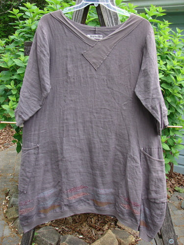 The Barclay Linen Crossover Urchin Dress features a V neckline, drop shoulders, empire waist, varied side lengths, and feather border, embodying Bluefishfinder.com's vintage, creative style.