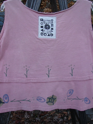 1993 Parallel Top Twig Ash Pink OSFA: A pink shirt with a design on it. Features a crop A-line cut, wide and rounded neckline, double-layered bodice, and a blue fish patch on the back. Bust 48, waist 48, hips 52, hem circumference 56, length 23 inches.