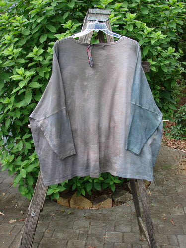 Barclay NWT Patched Supima Taos Mountain Tunic Belief Spirit Magic Peace Grey OSFA displayed on a clothes rack, showcasing its long sleeves and relaxed fit, embodying vintage Blue Fish Clothing's expressive style.