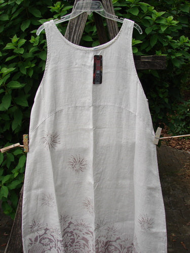 Barclay NWT Linen Sundress features sun designs in a natural fog pattern, hanging outdoors. This dress embodies Blue Fish Clothing's vintage charm and creative freedom.