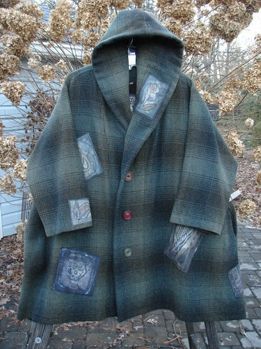 1995 Patched Hooded Autumn Jacket in Cottage Green Plaid. A cozy coat with oversized buttons, a double-lined hood, and deep side pockets. Features a variety of patches and foldable cuffs. Perfect for winter.