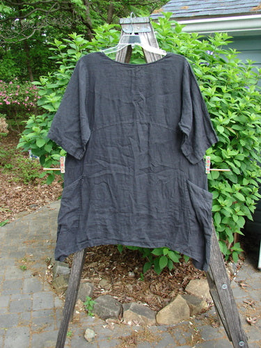 Barclay Linen Two Pocket Urchin Dress Falling Branch Black Size 1, featuring a rounded neckline, sectional panels, downward curved empire waist, varying side lengths, three-quarter sleeves, and double drop front wrap pockets.