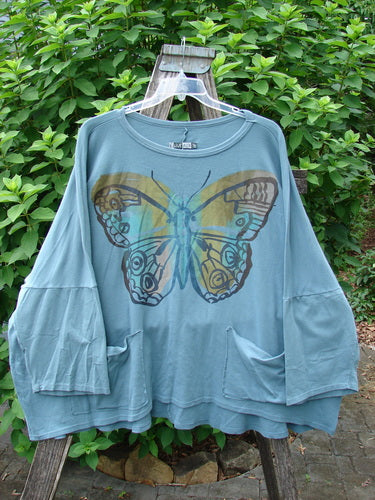 Barclay Two Pocket Mariposa Pullover Blue Sea OSFA features a delicately painted butterfly, capturing the essence of BlueFishFinder’s vintage style, offering creative expression through unique, artistic designs.