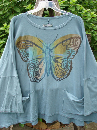 Barclay Two Pocket Mariposa Pullover Blue Sea OSFA displayed on a hanger, featuring a butterfly motif, embodying Bluefishfinder.com's vintage aesthetic and creative individuality for diverse women.