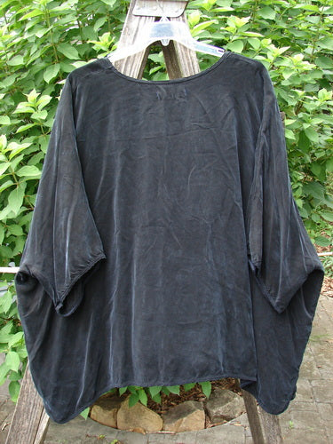 Barclay Velvety Cupro Drape Square Top Celtic Botanicals Black OSFA displayed on a wooden pole and a clothes rack, showcasing its elegant drape and unique design, reflecting Bluefishfinder.com's creative vintage style.