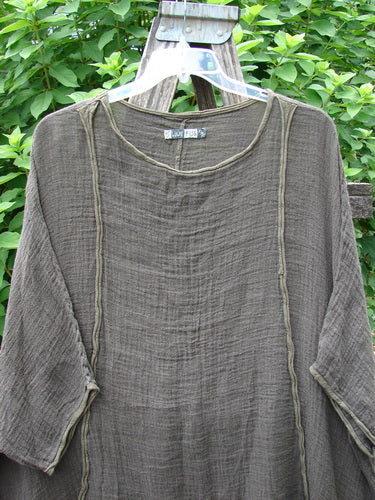 The Barclay Gauze Linen Exterior Curve Hi Low Pullover, displayed on a hanger, highlights its airy fabric and unique silhouette, embodying Blue Fish Clothing's commitment to individuality and vintage style.