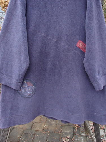 Barclay Celtic Moss Patched Highlander Coat in Deep Violet, featuring large vintage buttons, diagonal seams, and a unique front lower pocket, displayed on a textured brick surface.