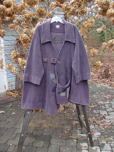 2000 PMU Celtic Moss Highlander Coat Aubergine Size 1: A purple coat on a clothes rack. Plush and heavy, made from incredible Celtic Moss. Features empire waistline, diagonal back, and multiple patches.
