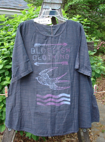 Barclay NWT Chambray Short Sleeved Promotional Top features a bird and arrow design. Its A-line shape and rounded hem showcase Blue Fish Clothing's creative expression, suitable for diverse body types.