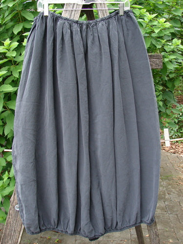 Barclay Silk Drawstring Bell Skirt Unpainted Raven OSFA draped over a wooden fence, showcasing its elegant pattern and flowing design, embodying the vintage charm of Bluefishfinder.com.