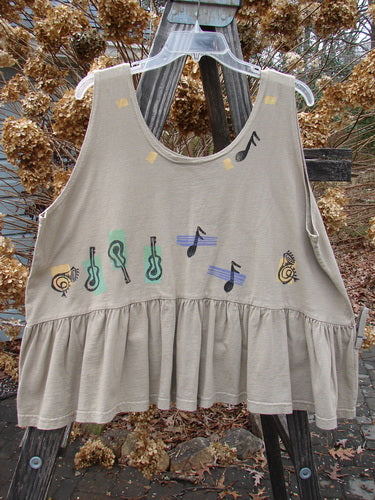 1992 Peplum Top Music Festival Wheat OSFA: A tan tank top with musical notes on it, featuring a yoked waist seam, rounded neckline, and wide waist measurement. Perfect for layering, this vintage flounce top is a rare find from the Summer Collection of 1992.
