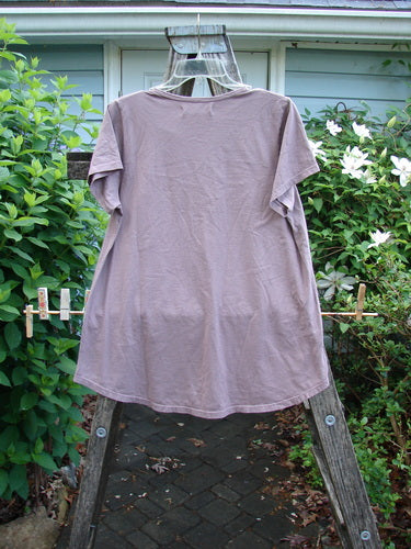 Barclay NWT Cap Sleeved Travel Tee in Rose Earth, featuring a rounded neckline, wide cap sleeves, and an A-line shape with varying hemline, adorned with a subtle soft single flower design.