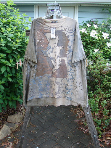 Barclay NWT Art Tee Mountain Dove Cafe Au Lait OSFA features a tunic length, drop shoulders, loose three-quarter sleeves, and a rounded neckline, showcasing the Mountain Dove theme with a varying hemline.