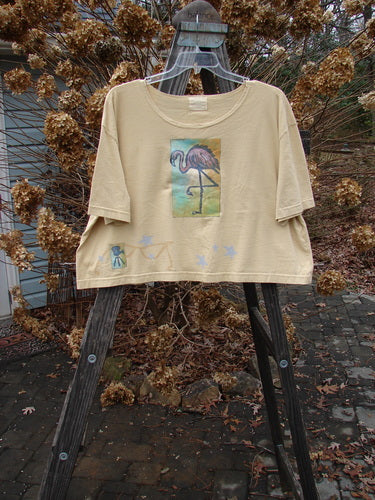 2000 Short Sleeved Crop Tee Flamingo Plantain Size 2 displayed on a hanger, featuring a colorful flamingo design, wide swingy shape, and softly rolled neckline, made from organic cotton.