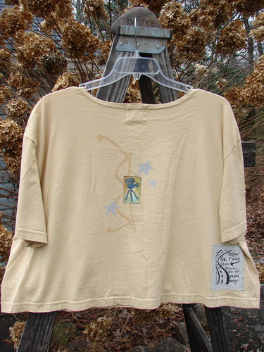 2000 Short Sleeved Crop Tee Flamingo Plantain Size 2, featuring a playful crop shape, colorful flamingo design, wide swingy lower shape, and softly rolled neckline, displayed on a wooden swing.