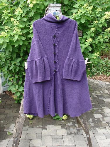 Barclay Patched Celtic Moss Double Snap Button Back Coat Violet OSFA drapes elegantly on a wooden ladder, showcasing its high collar, bell sleeves, and decorative front toggles, embodying Bluefishfinder.com's vintage charm.