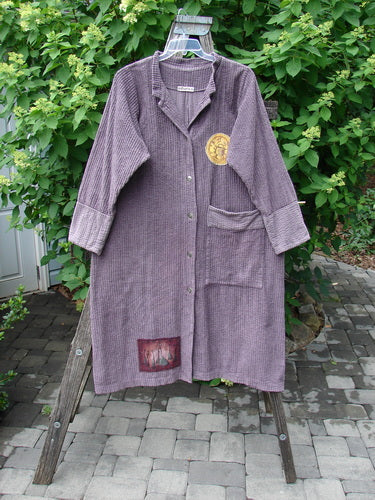 Barclay Patched Chenille Straight Coat Aubergine Dust Size 1, featuring a textured weave, snap buttons, rollable cuffs, notched lapel, decorative patches, and a single patch pocket, displayed on a stepladder outdoors.